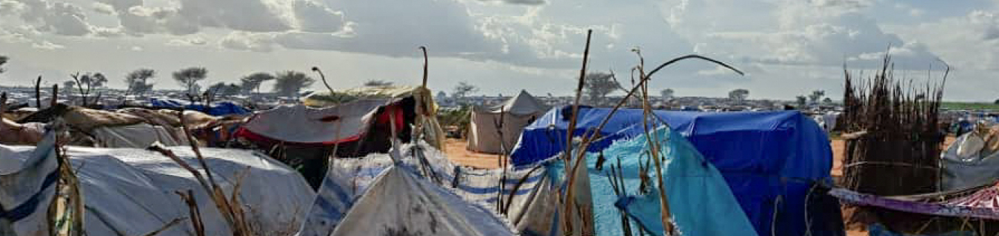 Camp von Geflüchteten aus dem Sudan in Adré, Ost-Tschad Plastikplanen sind auf Stöckern im Kreis gespannt, dahinter Zelte