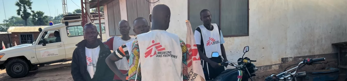 Fünf Männer in Ärzte ohne Grenzen Shirts neben Motorrädern