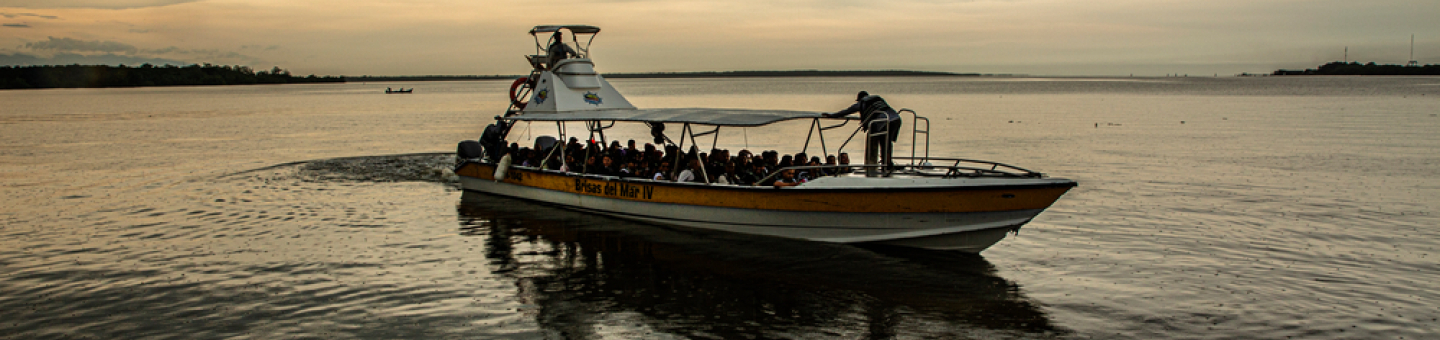 Der Darién-Dschungel liegt in Ecuador, Kolumbien und Panama. Menschen in einem Kahn auf einem breiten Fluss