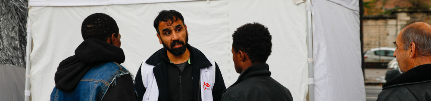 Zusätzlich zu unserer mobilen Klinik haben wir in Calais nun eine Notunterkunft eröffnet. Migranten und ein Mitarbeiter vor einer mobilen Klinik in Calais
