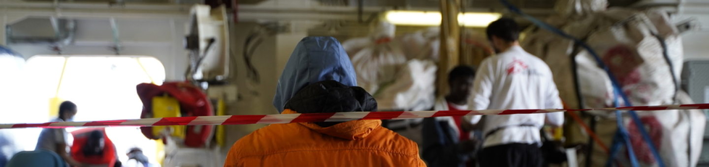 Im Januar 2023 wurde ein weiteres Boot in Seenot auf der gefährlichsten Migrationsroute der Welt von unserem Team auf der Geo Barents gesichtet. Bild in Schiff mit Mitarbeitenden und Geretteten im Hintergrund