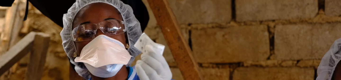 Eine Person in Schutzkleidung bereitet eine Ebola-Impfung vor.