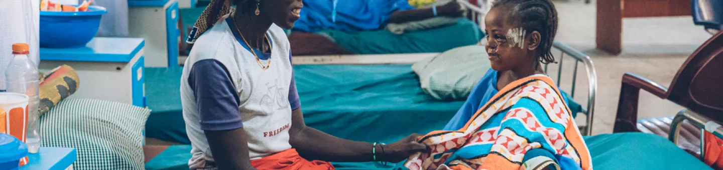 Eine Mutter und ihre 6-jährige Tochter sitzen auf einem Krankenbett.