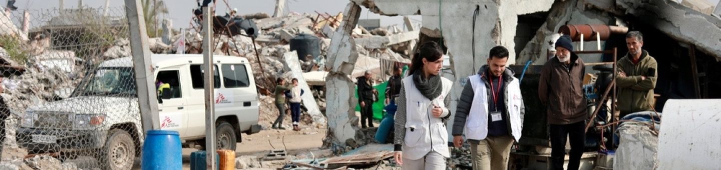 Im Gazastreifen mangelt es an dem Nötigsten. Die Blockade verhindert die Einfuhr dringedn benötigter Güter. Gaza Blockade: Mitarbeitende laufen zwischen zerstörten Gebäuden
