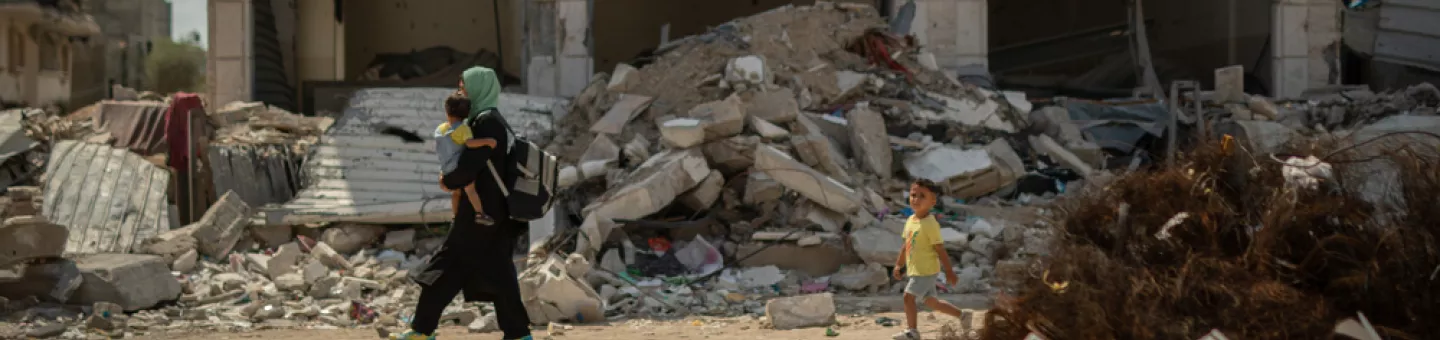 Frau trägt Kind durch Trümmer in Gaza-Stadt.