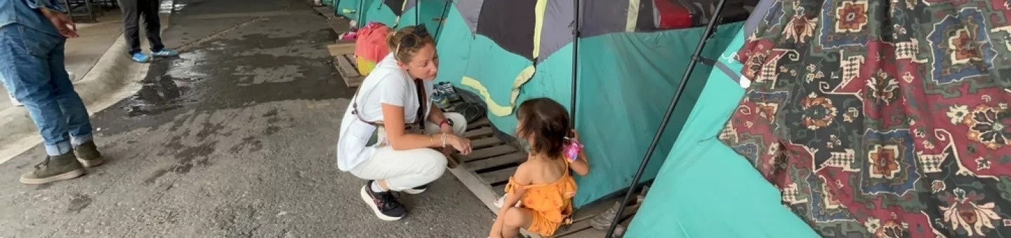 Kniende Mitarbeitende spricht mit Kind