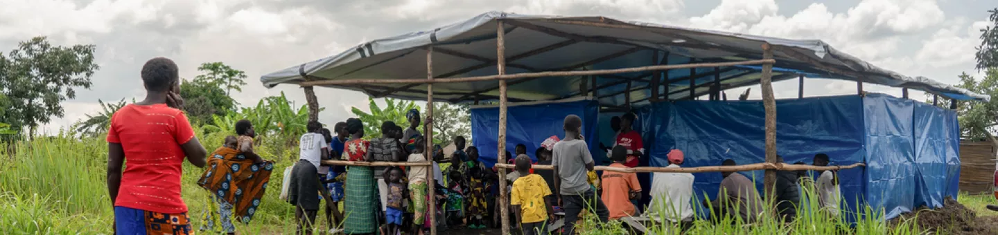 Menschen stehen vor Hütte aus Planen