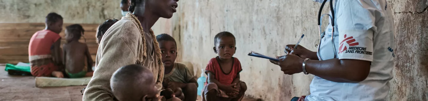 Eine Mitarbeiterin von Ärzte ohne Grenzen sitzt einer Patientin mit Kind gegenüber