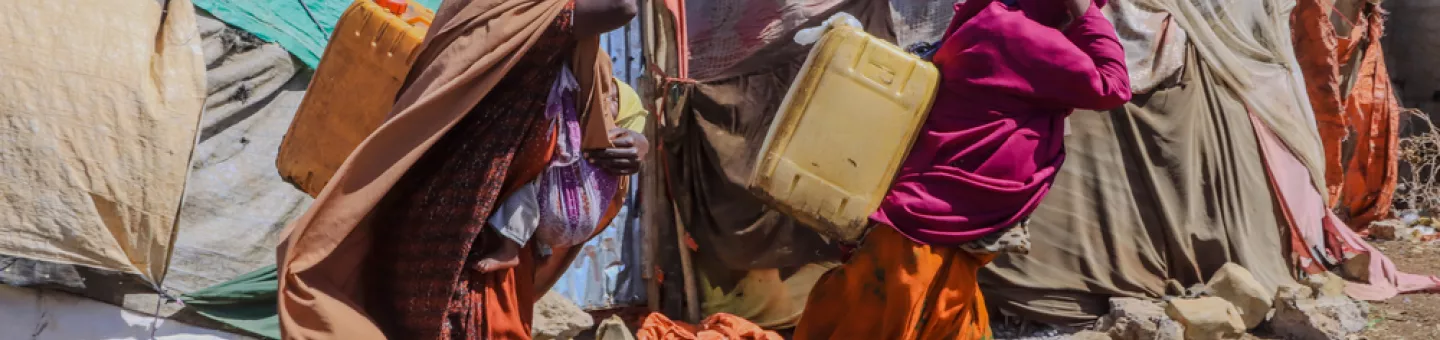 Zwei Frauen tragen Wasserkanister in Camp