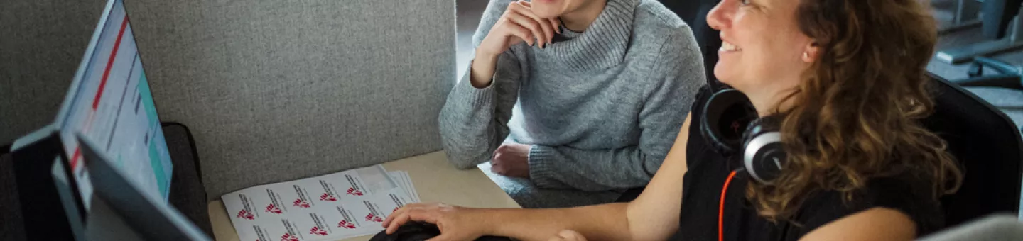 Zwei Mitarbeitende am Schreibtisch vor dem Computer