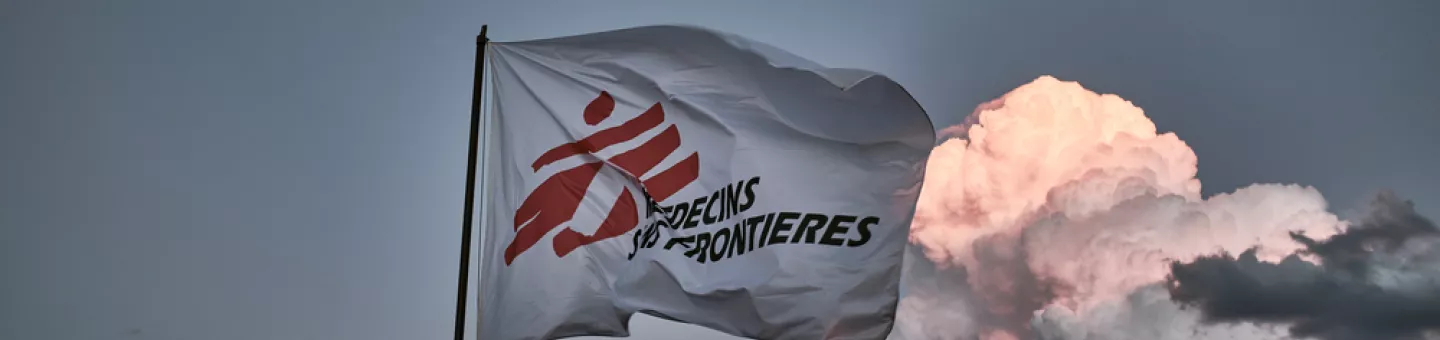 Flagge mit Logo von Ärzte ohne Grenzen vor bewölktem Himmel