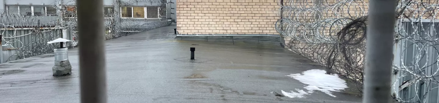 Gitterstäbe vor einem Dach, das mit Stacheldrahtzaun gesichert wurde