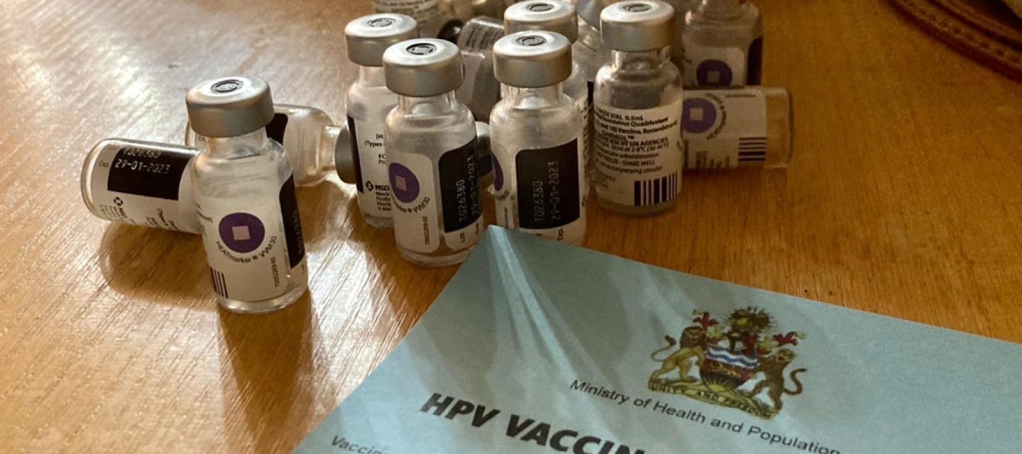 Auf einem Tisch stehen HPV Impfdosen und ein Impfzertifikat.