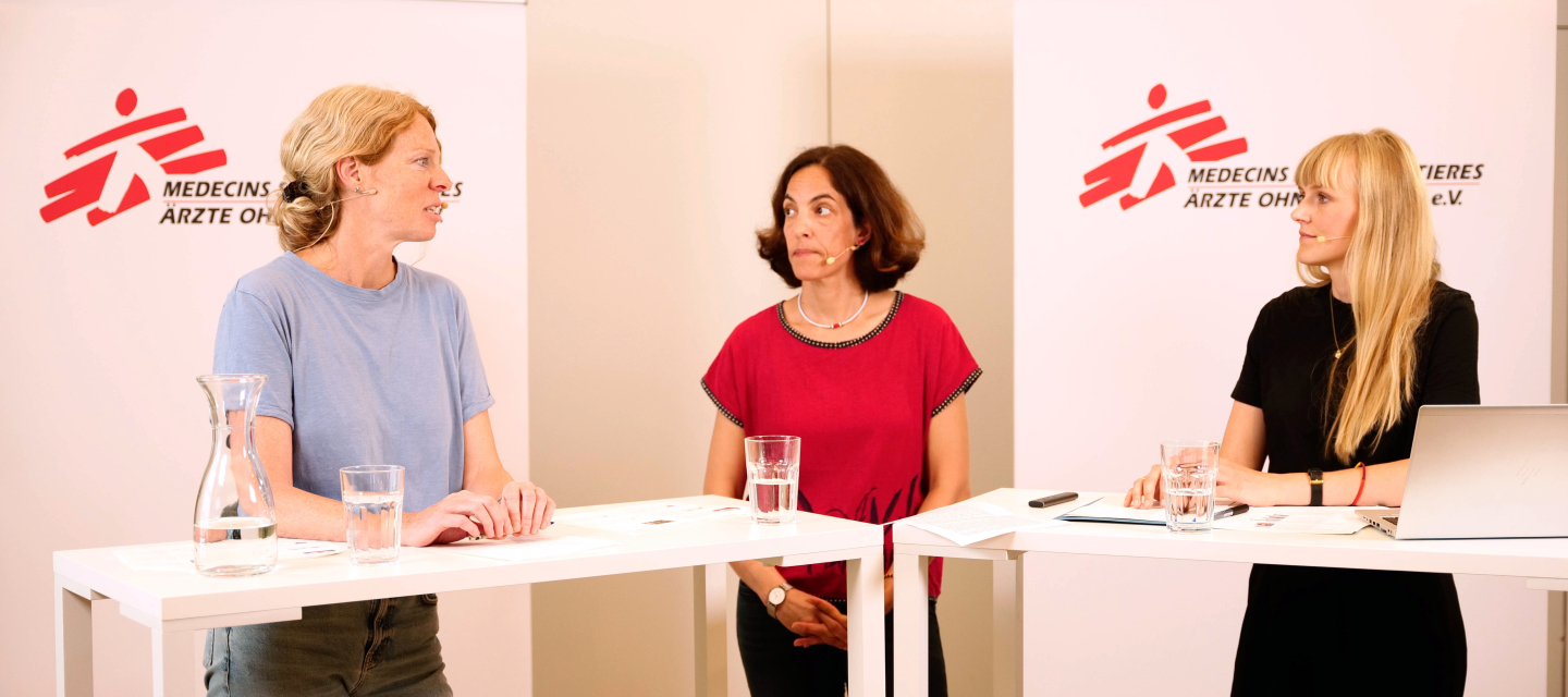 ThemenTalk Hero Drei Frauen stehen an Präsentationstischen und sprechen über ihre Forschung und Arbeit.