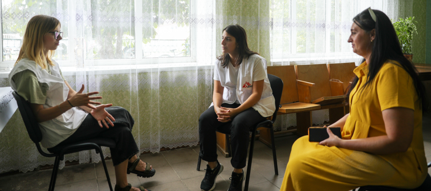 Mit mobilen Teams bieten wir vor Ort in betroffenen Regionen der Ukraine Hilfe an. Drei Frauen in Stuhlkreis im Gespräch miteinander, eine ist Projektkoordinatorin