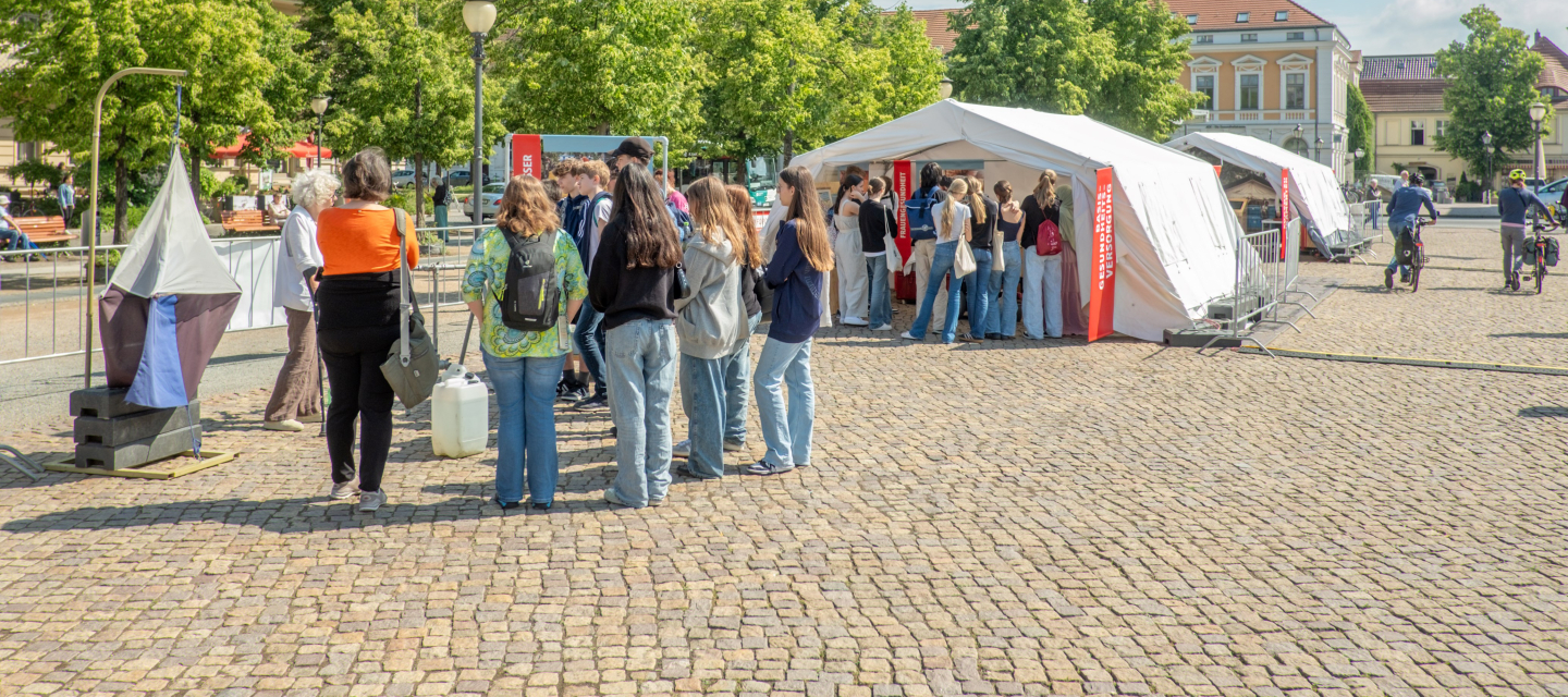 Menschenansammlung vor Zelten der Freiluftausstellung