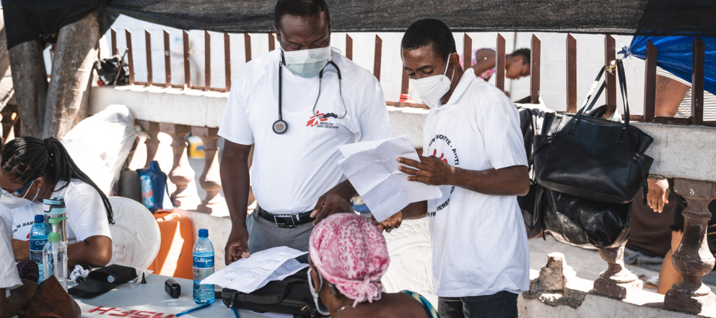 Zwei Ärzte sprechen mit einem Patienten in einem Camp für Vertriebene