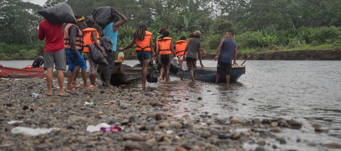 Menschen mit Rettungswesten steigen in ein Kanu auf einem Fluss ein