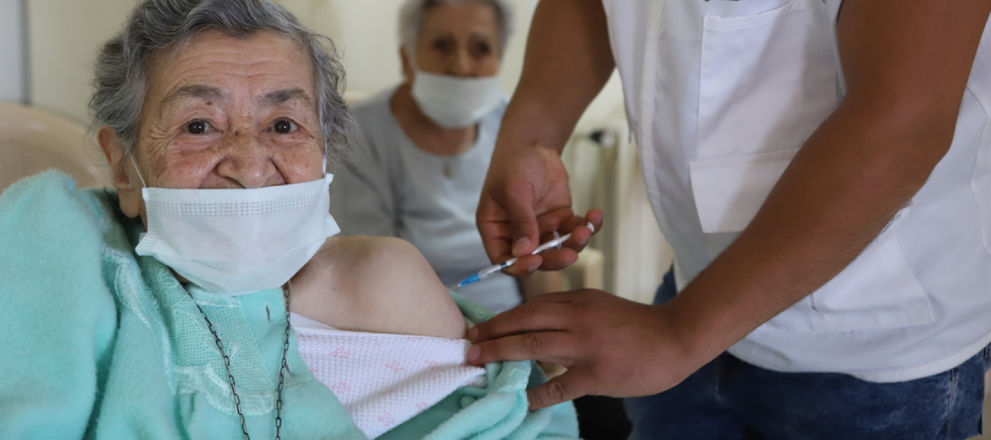 Ein Mitarbeiter von Ärzte ohne Grenzen impft die Bewohnerin eines Altersheims im Libanon gegen Covid-19. Covid-19-Impfung Libanon Impfstoffproduktion globaler Süden