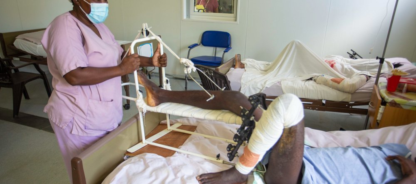 Eine Krankenpflegerin steht am Bett eines Patienten, der während des Erdbebens den Fuß gebrochen hat.