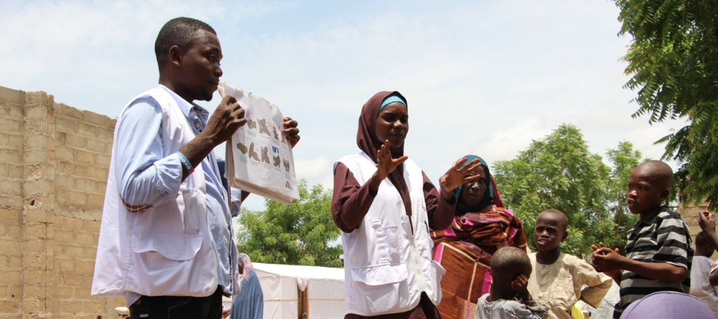 Mitarbeiter*innen der Gesundheitsförderung sprechen mit Vertriebenen in einem Camp in Borno