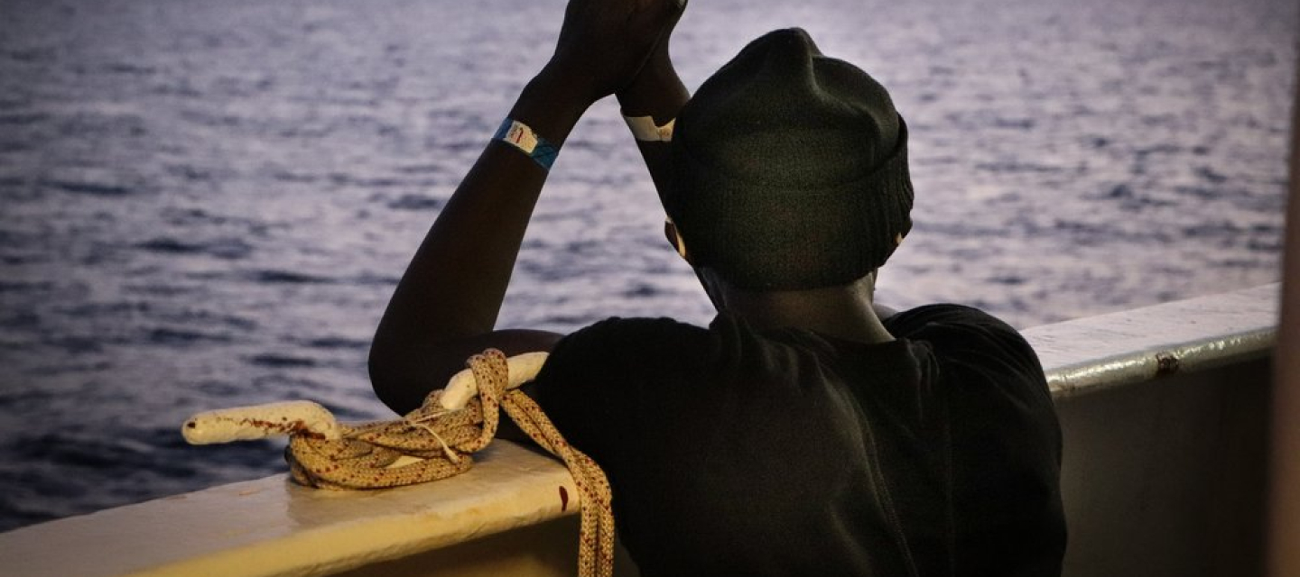An der Reling der Sea Watch 4 schaut eine gerettete Person aufs Meer