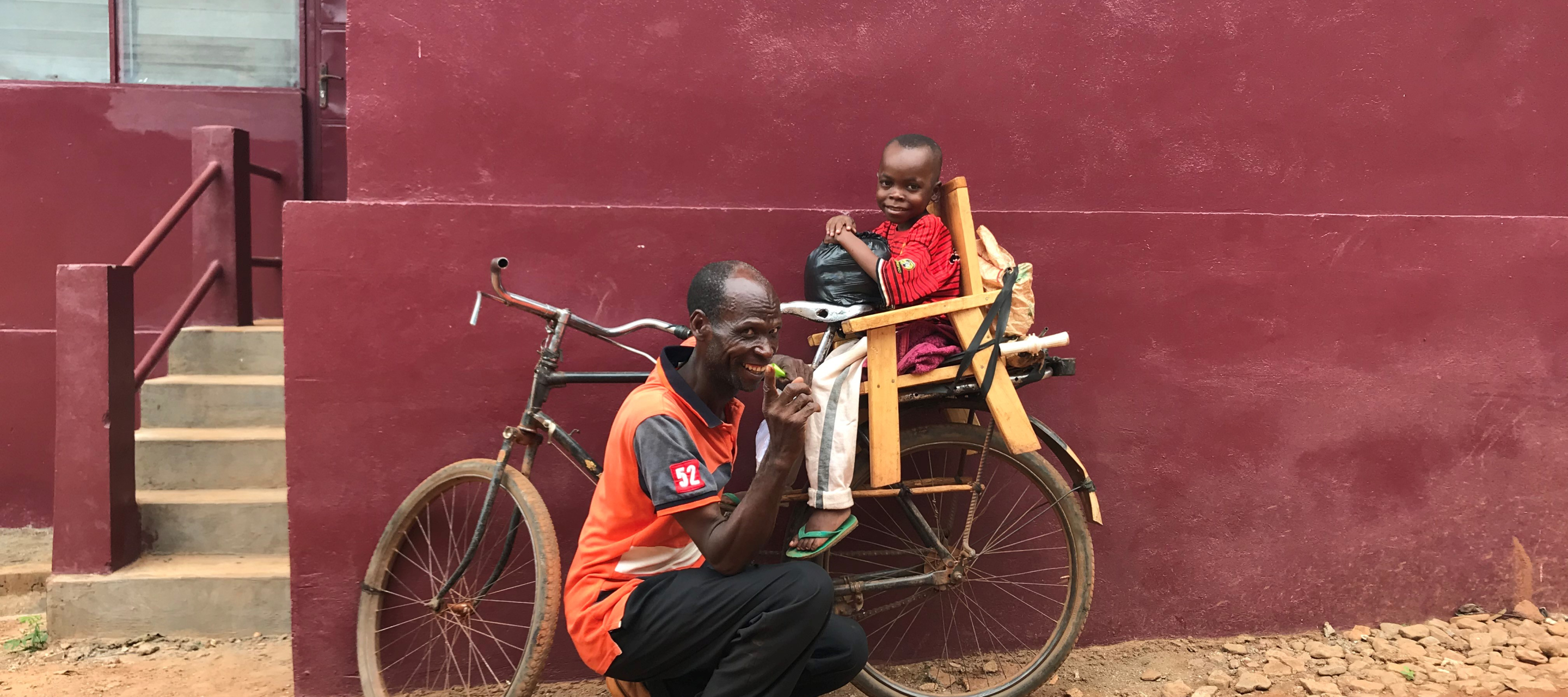 Der 8-jährige Dieu-Beni und sein Vater auf einem Fahrrad.
