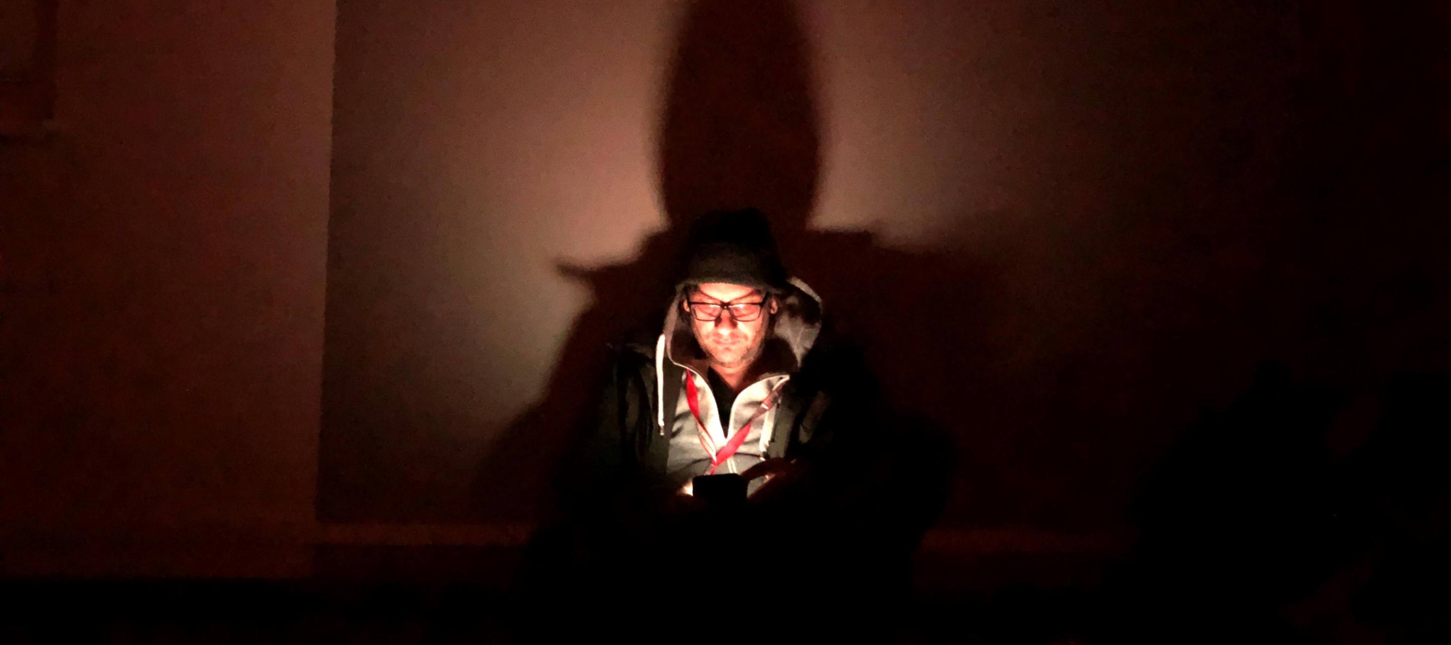 Oliver Barth schut in einem dunklen Luftschutzkeller auf sein Handy