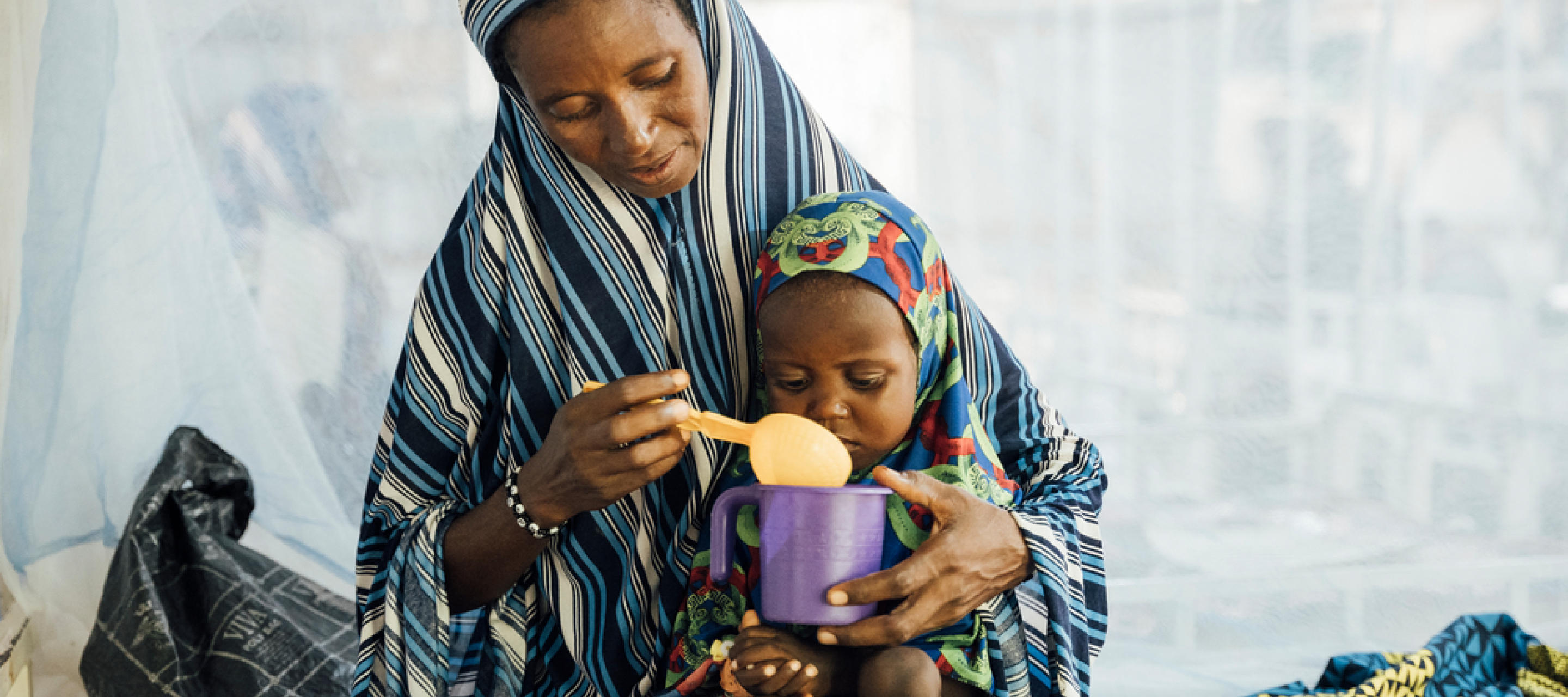 Eine Mutter füttert ihre 2-jährige Tochter auf der Mangelernährungsstation in einem Krankenhaus in Niger