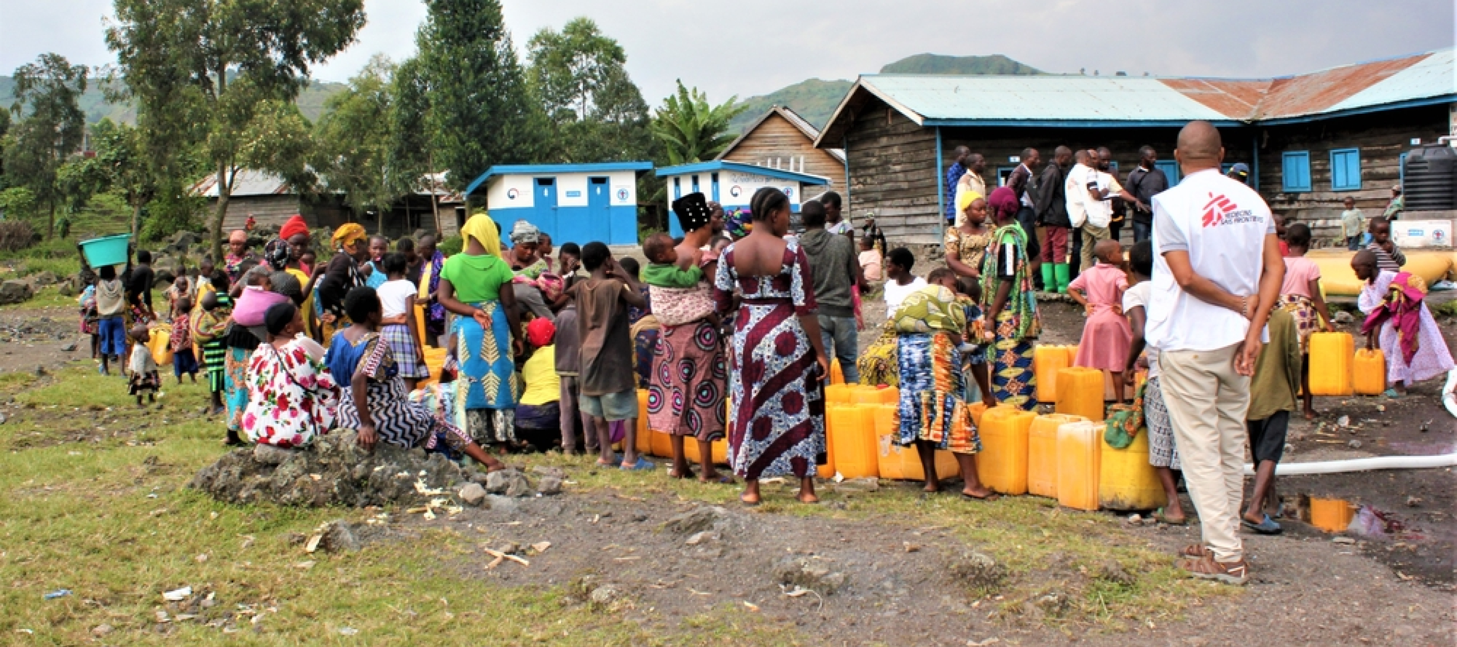 Die Bewohner*innen der Geflüchtetenunterkunft warten darauf, ihre Kanister mit Trinkwasser zu füllen 