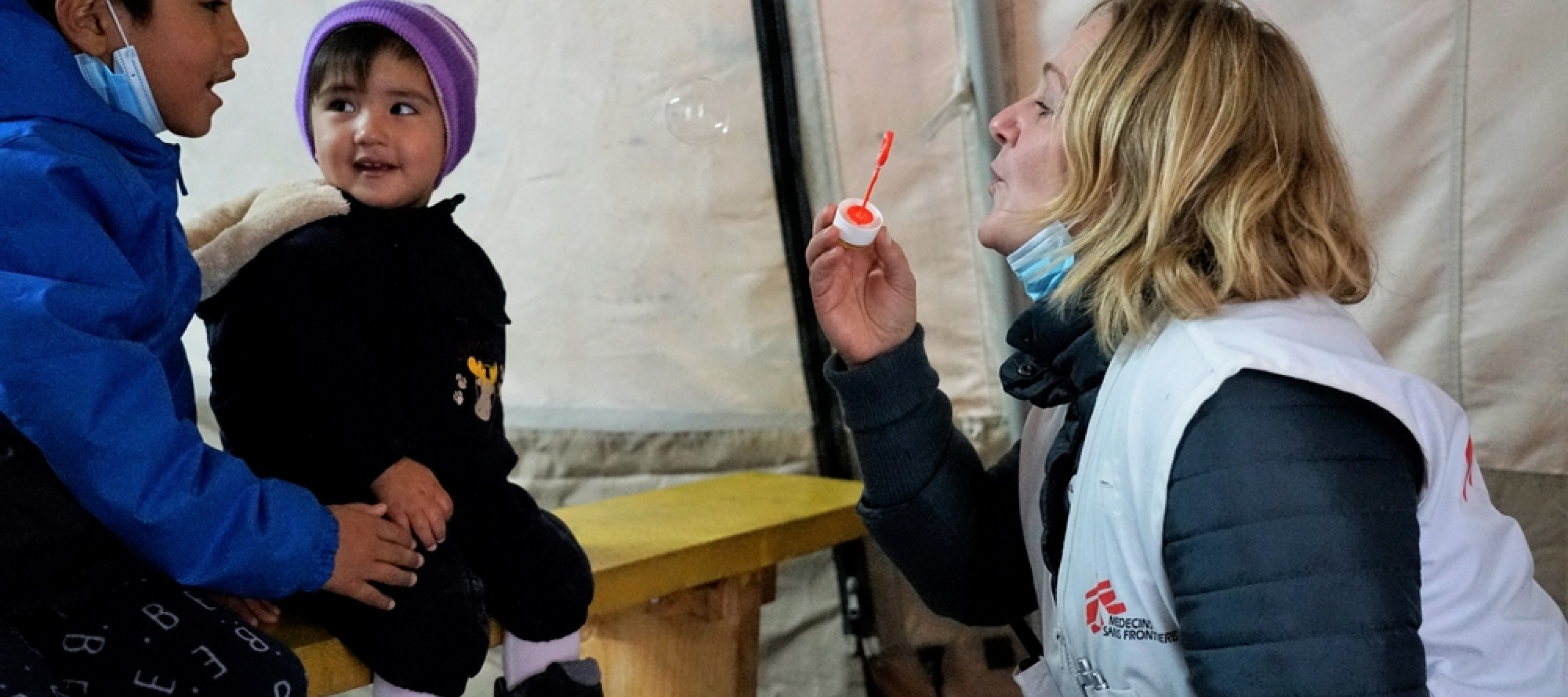 Mitarbeiterin spielt mit geflüchteten Kindern mit Seifenblasen auf Lesbos.