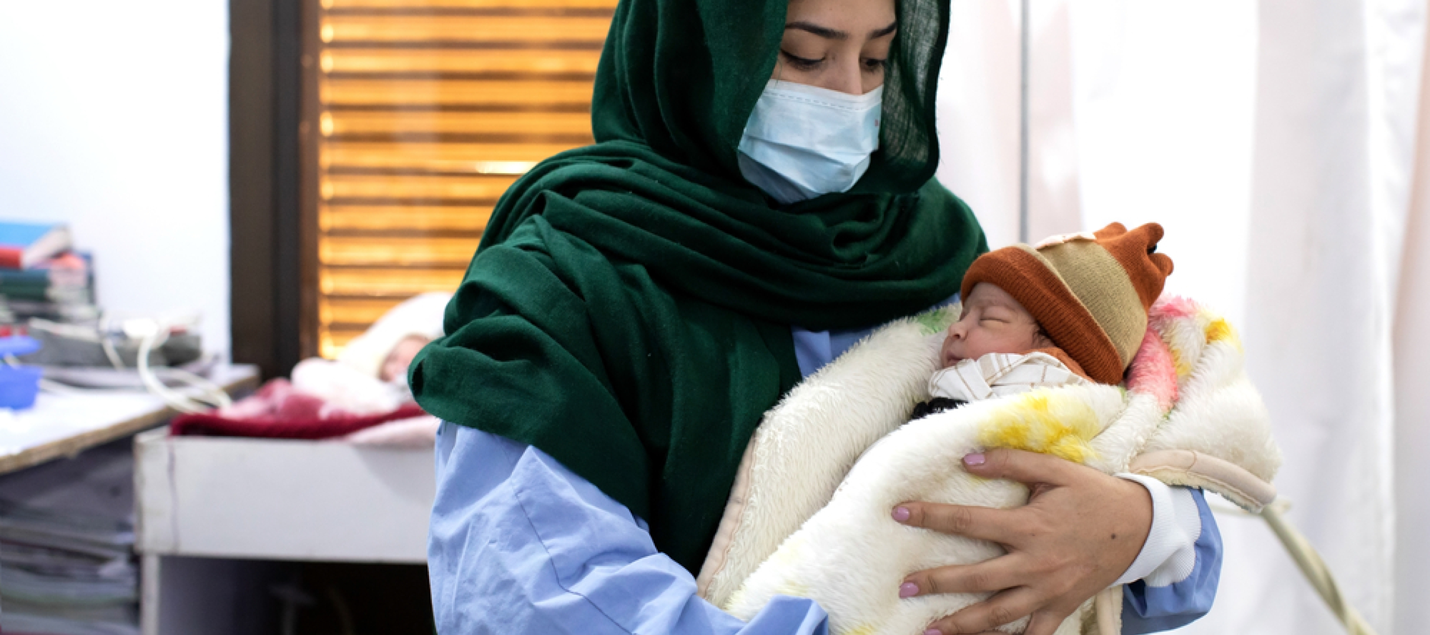 Eine Mitarbeiterin in Pakistan hält ein Neugeborenes auf ihrem Arm.