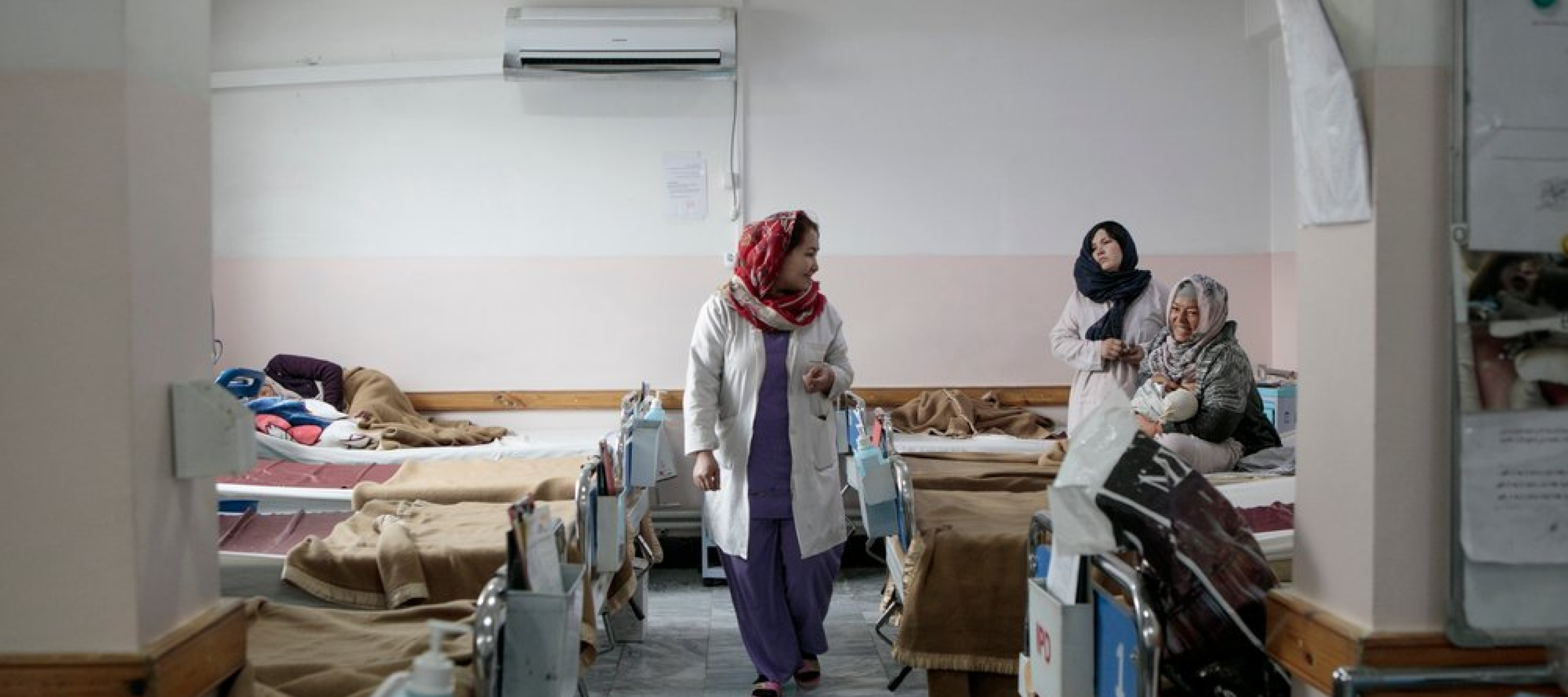 Eine Mitarbeiterin von Ärzt ohne Grenzen läuft durch den Ruhesaal nach der Geburt mit vielen Betten 