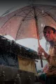 Ein Mann hält während es regnet einen Regenschirm.