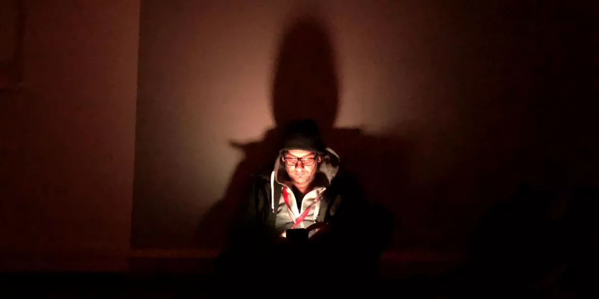 Oliver Barth schut in einem dunklen Luftschutzkeller auf sein Handy