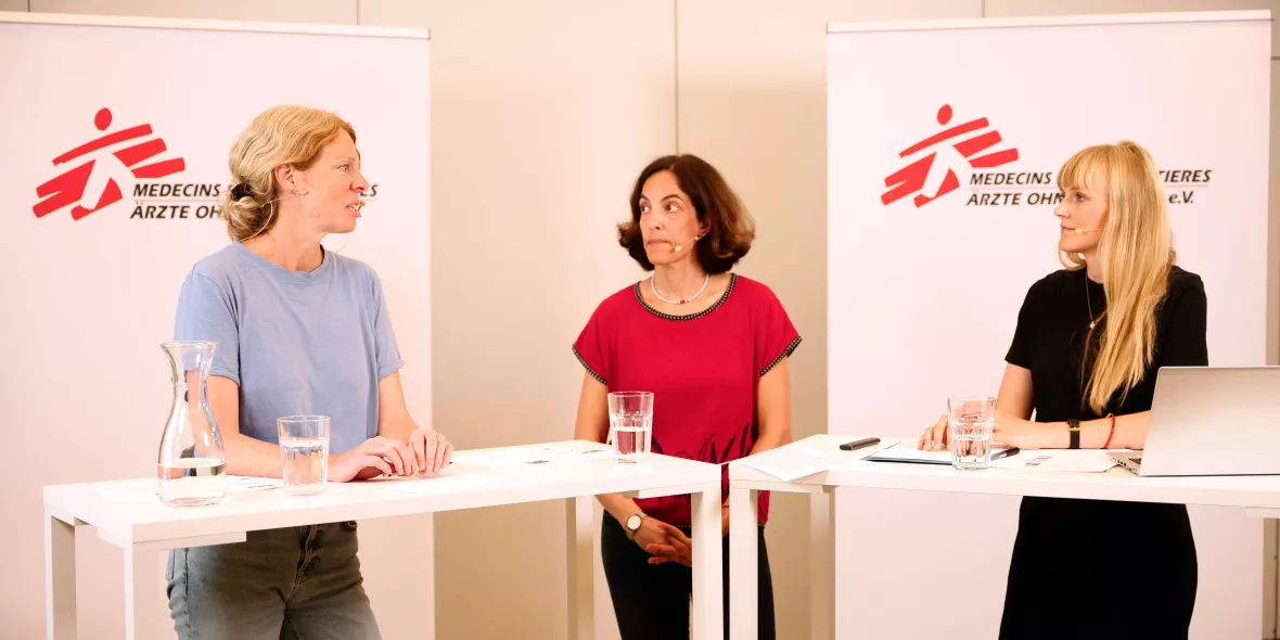 Drei Frauen stehen an Präsentationstischen und sprechen über ihre Forschung und Arbeit.