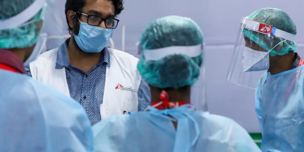 Vier Ärzte beraten sich. Sie sind komplett in Schutzkleidung gehüllt.