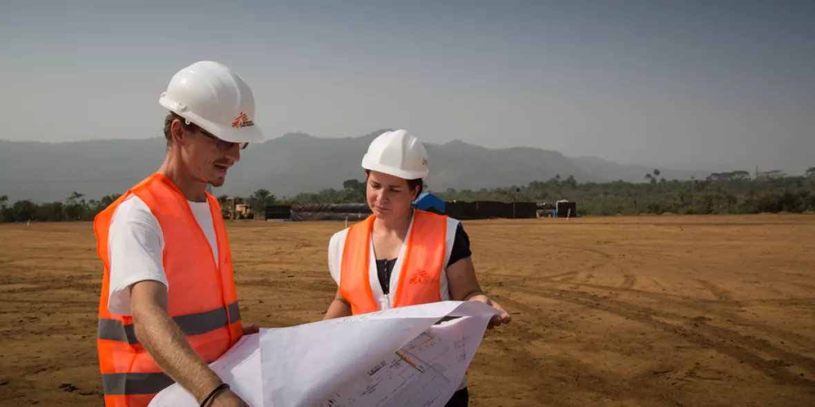 Zwei Mitarbeiter*innen mit Berufsprofil Architekt*in, Bauingenieur*in  auf Gelände mit Bauplan