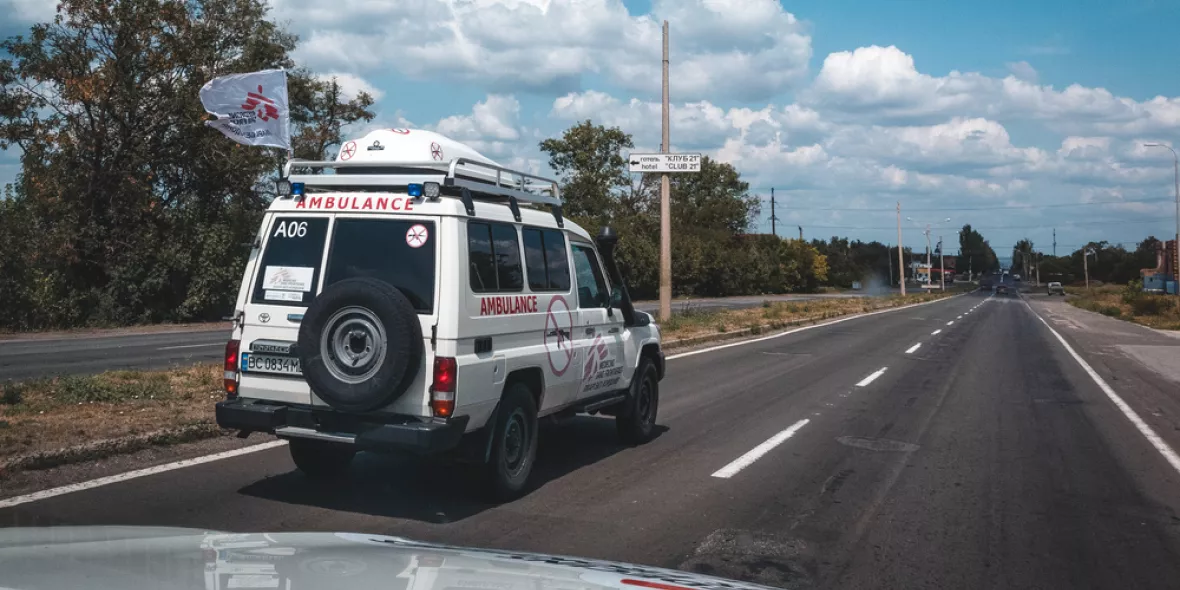 Ein weißer Krankenwagen mit dem Logo von Ärzte ohne Grenzen fährt auf einer Straße.