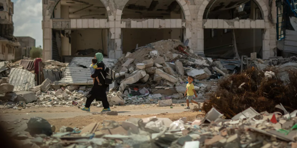 Frau trägt Kind durch Trümmer in Gaza-Stadt.