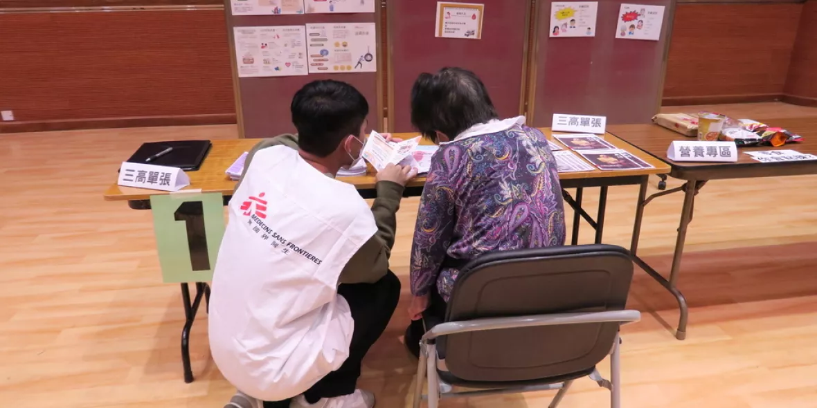 Mitarbeiter in Gespräch mit Patientin an Tisch