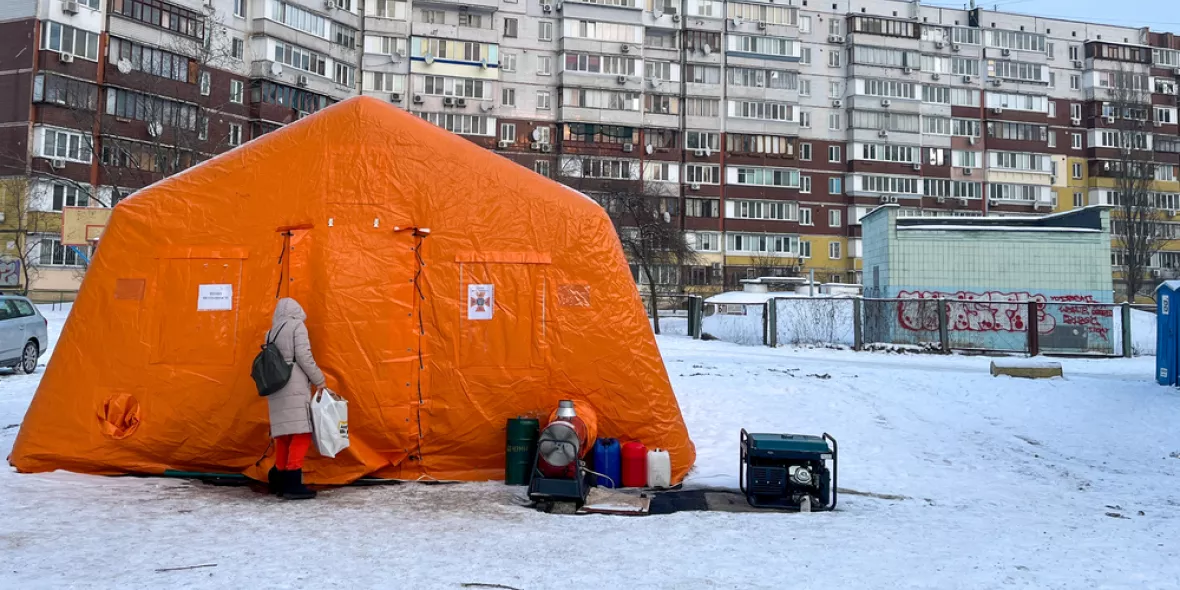 Zelt im Schnee - davor Person neben Generator
