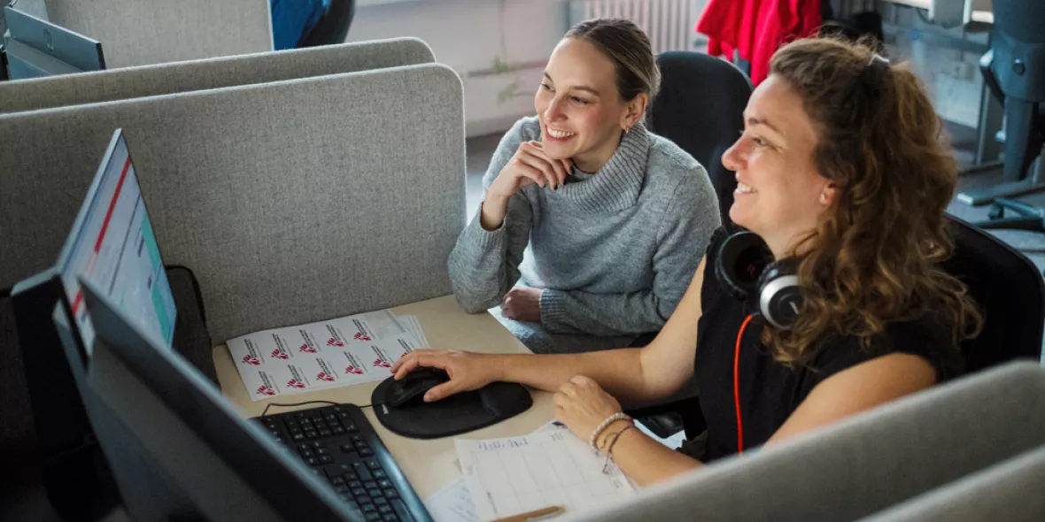 Zwei Mitarbeitende am Schreibtisch vor dem Computer