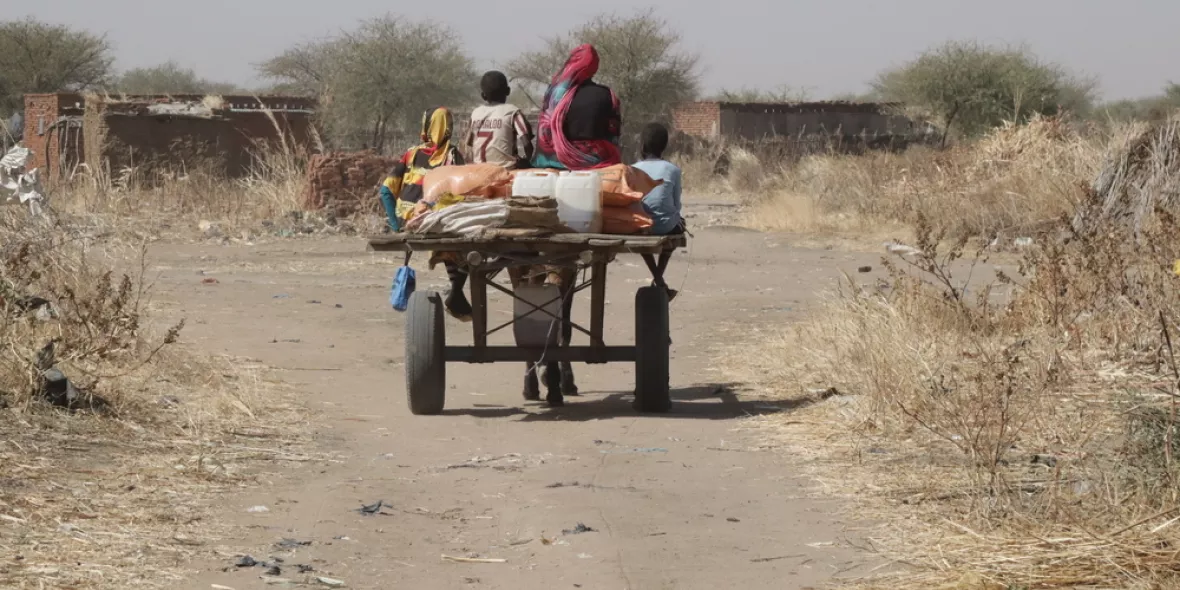 Eine Frau und zwei Kinder fahren auf einem Pfedewagen mit ihrer Ration Lebensmittel