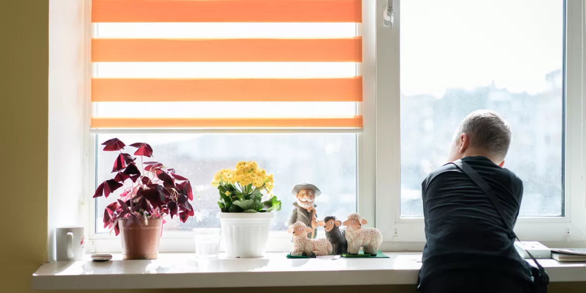 Ein Junge lehnt an einer Fensterbank und schaut aus dem Fenster