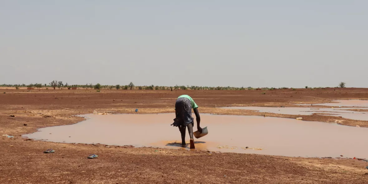 Person schöpft Regenwasser vom Boden