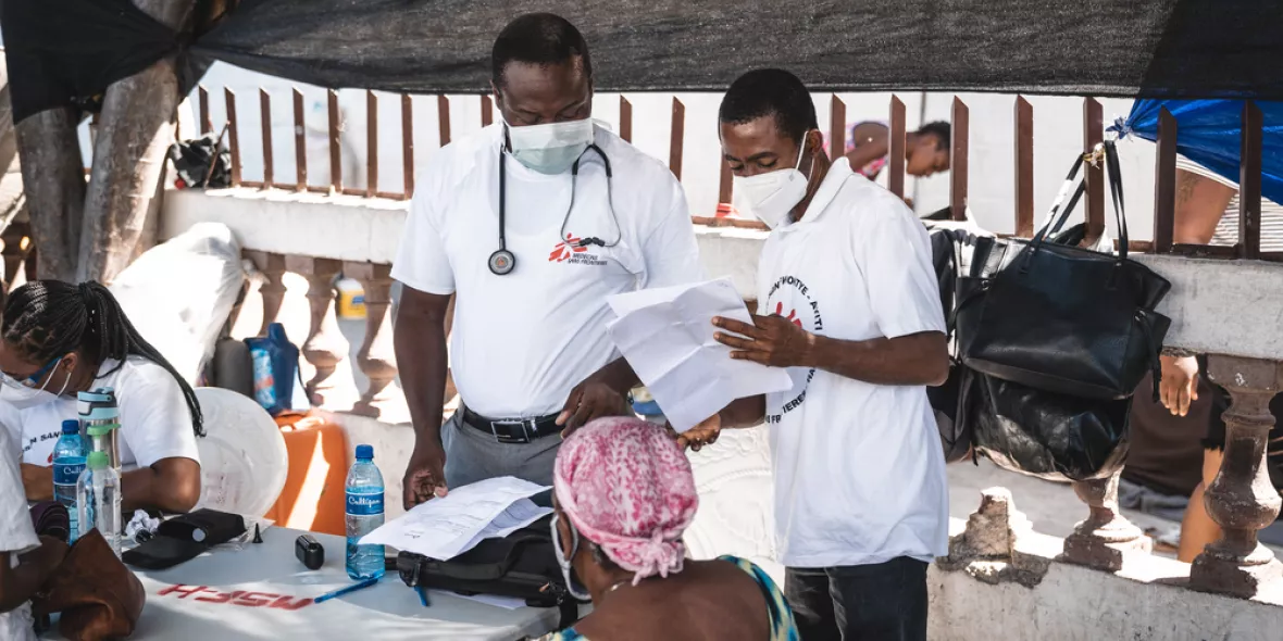 Zwei Ärzte sprechen mit einem Patienten in einem Camp für Vertriebene