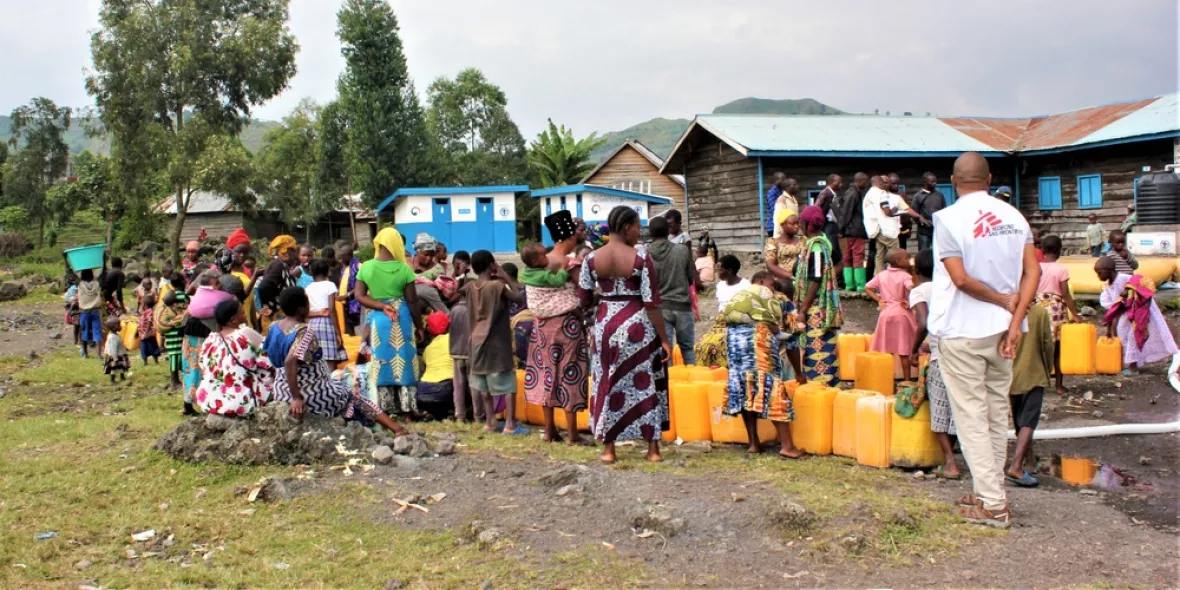 Die Bewohner*innen der Geflüchtetenunterkunft warten darauf, ihre Kanister mit Trinkwasser zu füllen 