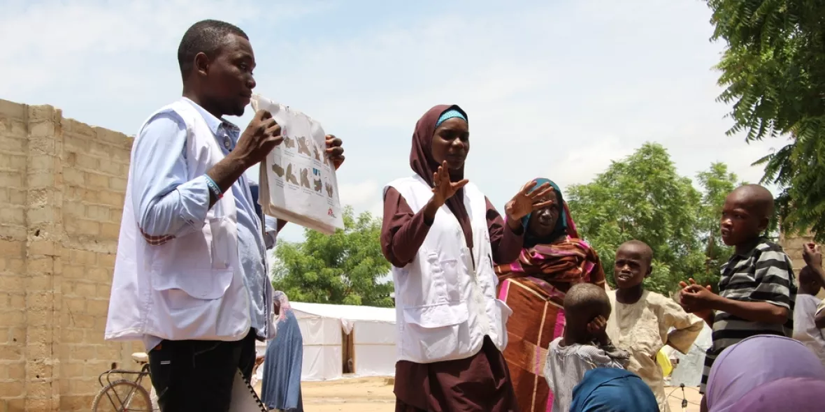 Mitarbeiter*innen der Gesundheitsförderung sprechen mit Vertriebenen in einem Camp in Borno