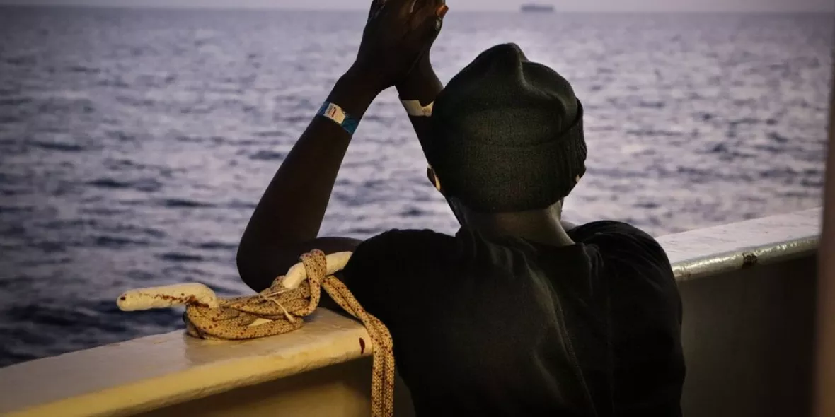 An der Reling der Sea Watch 4 schaut eine gerettete Person aufs Meer